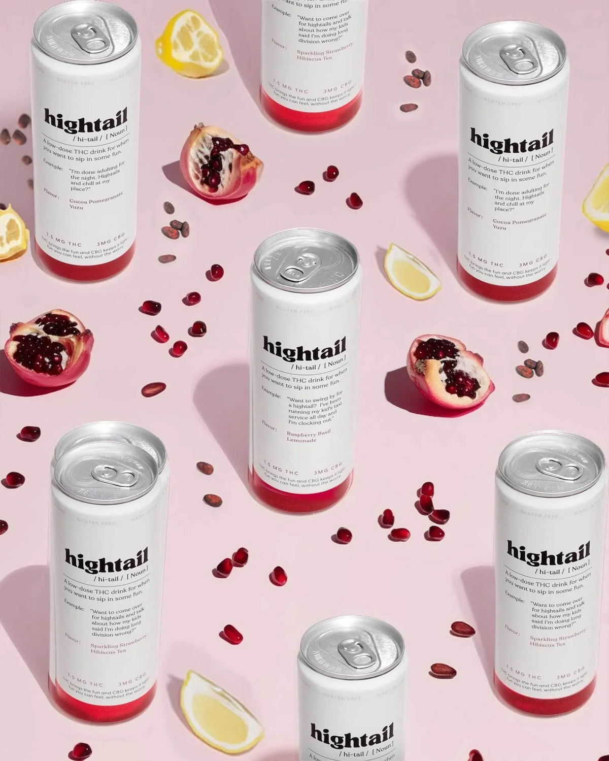 Cans of 'hightail' on a pink background with pomegranate seeds and lemon slices.